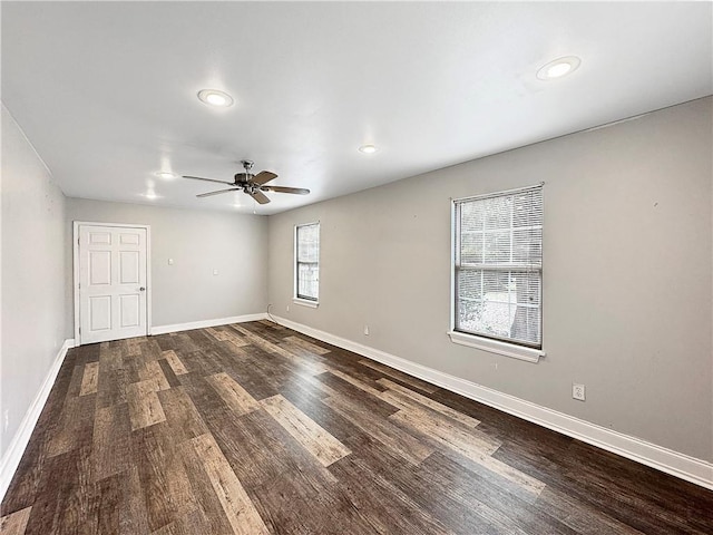 empty room with a wealth of natural light, dark hardwood / wood-style flooring, and ceiling fan