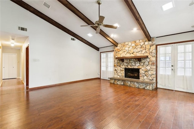 unfurnished living room featuring beam ceiling, ceiling fan, french doors, hardwood / wood-style floors, and a fireplace