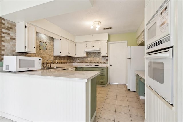 kitchen with sink, backsplash, kitchen peninsula, white appliances, and white cabinets