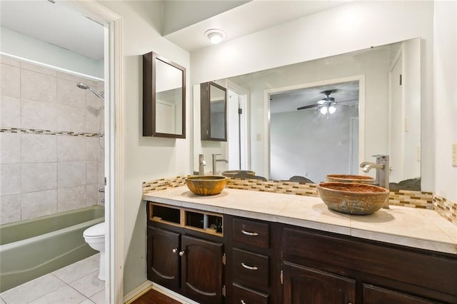 full bathroom featuring vanity, decorative backsplash, ceiling fan, toilet, and tiled shower / bath combo