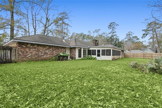 rear view of property featuring a yard and a sunroom