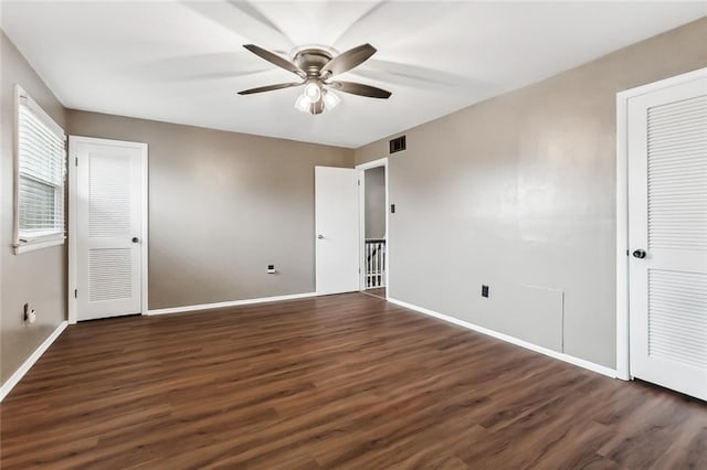 unfurnished bedroom with multiple closets, ceiling fan, and dark hardwood / wood-style flooring