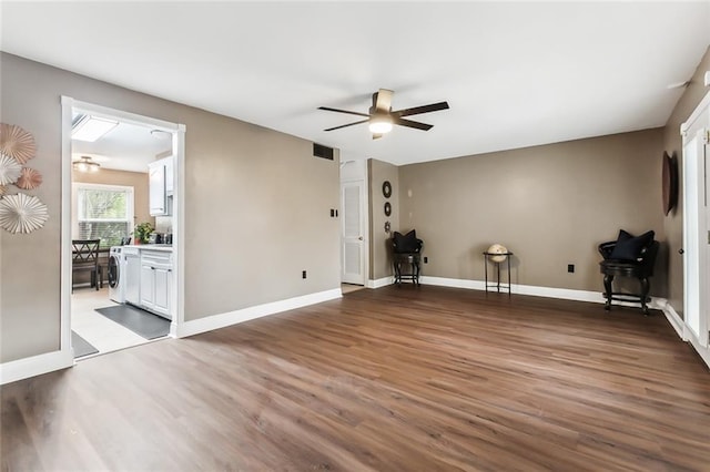 interior space featuring washer / clothes dryer, ceiling fan, and dark wood-type flooring