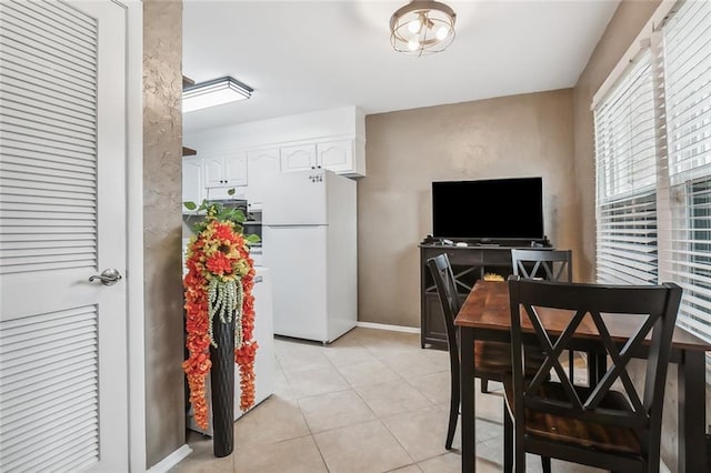 interior space with white cabinets, white refrigerator, and light tile patterned floors