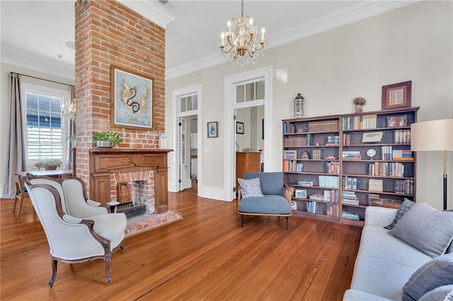 living area featuring hardwood / wood-style floors, a chandelier, ornamental molding, and a brick fireplace