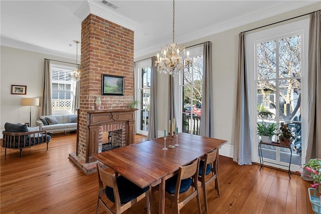 dining area featuring a fireplace, wood-type flooring, plenty of natural light, and ornamental molding