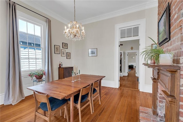 dining room with a notable chandelier, crown molding, and light hardwood / wood-style flooring