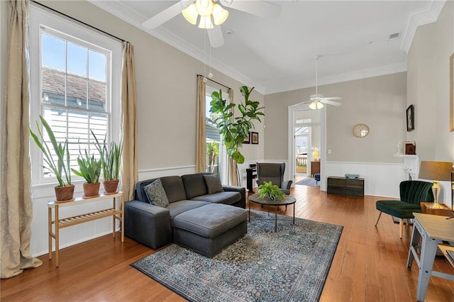 living room featuring hardwood / wood-style flooring, ceiling fan, and crown molding