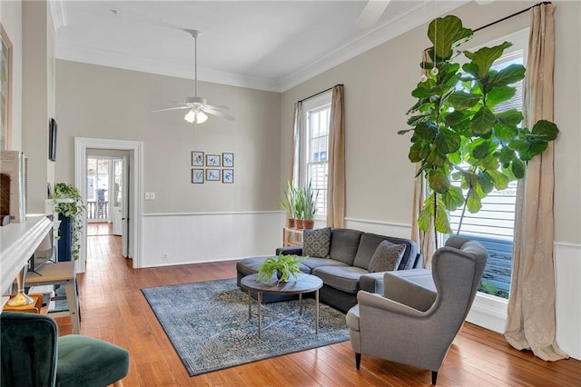 living room with hardwood / wood-style flooring, ceiling fan, and crown molding