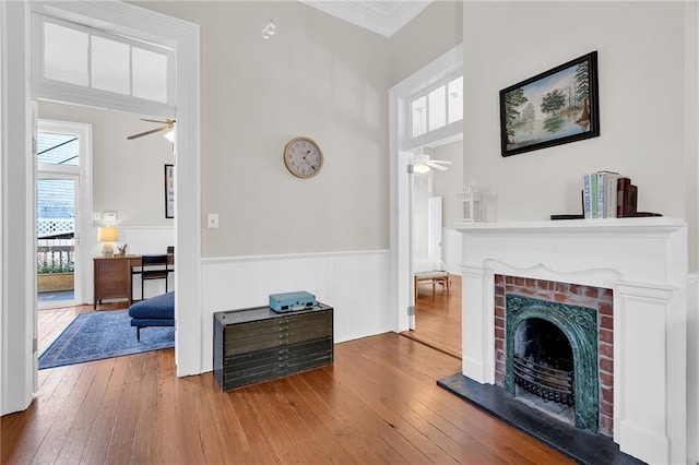 living room featuring ceiling fan, a fireplace, hardwood / wood-style floors, and ornamental molding