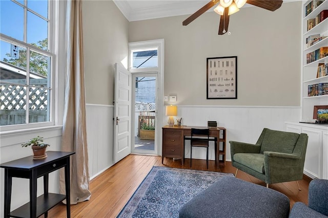 sitting room with ceiling fan, built in features, light wood-type flooring, and ornamental molding