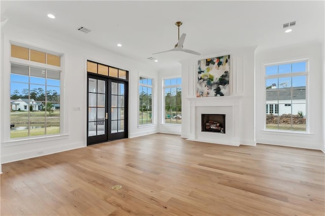 unfurnished living room with french doors, light wood-type flooring, and ceiling fan