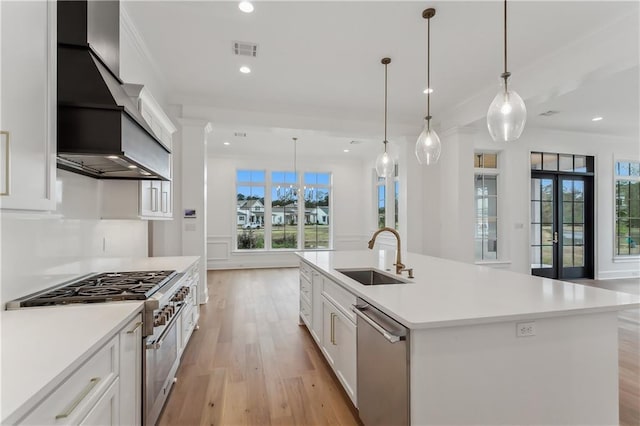 kitchen with pendant lighting, white cabinets, sink, an island with sink, and stainless steel appliances