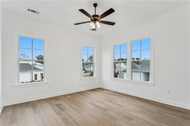 spare room with ceiling fan, plenty of natural light, and light wood-type flooring