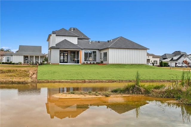 back of property with a lawn and a water view