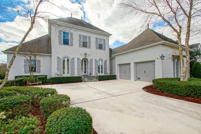 colonial home with stucco siding, a garage, and concrete driveway