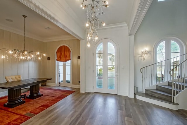 entryway featuring arched walkways, ornamental molding, wood finished floors, and a chandelier