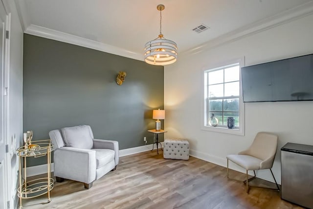 living area with an inviting chandelier, crown molding, and wood-type flooring