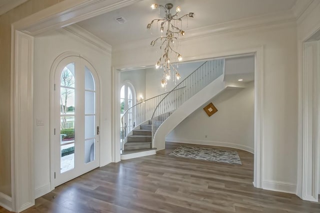 entrance foyer featuring french doors, dark hardwood / wood-style flooring, an inviting chandelier, and ornamental molding