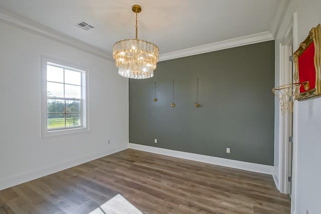 unfurnished room featuring visible vents, wood finished floors, ornamental molding, and an inviting chandelier