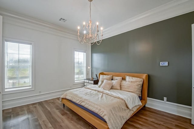 bedroom with a notable chandelier, ornamental molding, and hardwood / wood-style flooring