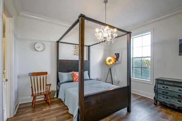 bedroom with an inviting chandelier, dark hardwood / wood-style flooring, and crown molding