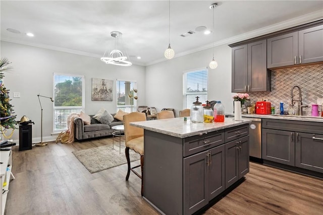 kitchen with a center island, sink, hanging light fixtures, hardwood / wood-style flooring, and a breakfast bar area