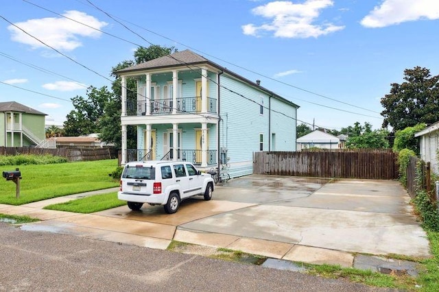 view of front of house with a porch, a balcony, and a front yard