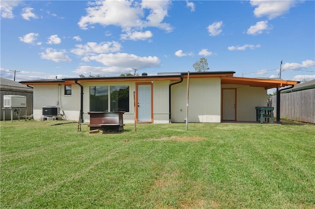 rear view of house with cooling unit and a yard