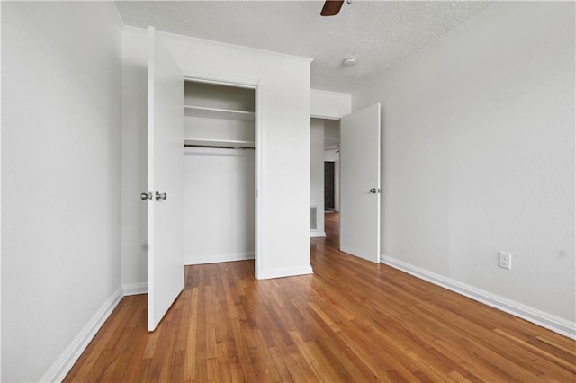 unfurnished bedroom with ceiling fan, wood-type flooring, and a textured ceiling