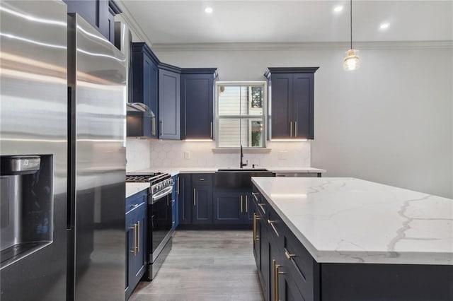 kitchen featuring appliances with stainless steel finishes, blue cabinetry, light stone counters, and sink