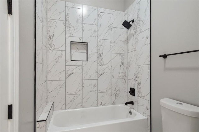 bathroom with toilet and tiled shower / bath