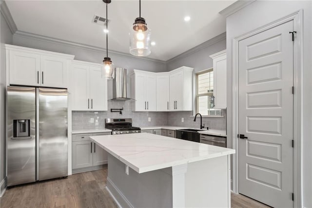 kitchen with wall chimney range hood, white cabinets, a center island, and stainless steel appliances