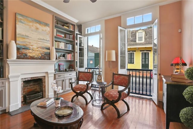 sitting room with hardwood / wood-style floors, built in features, and crown molding