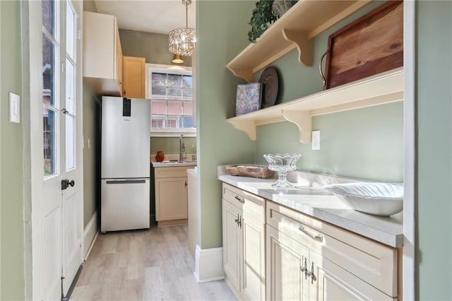 kitchen with hanging light fixtures, light hardwood / wood-style floors, fridge, and sink