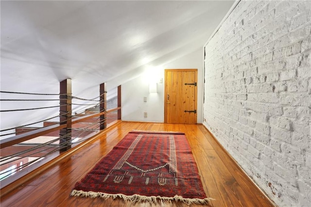 corridor with lofted ceiling and hardwood / wood-style flooring