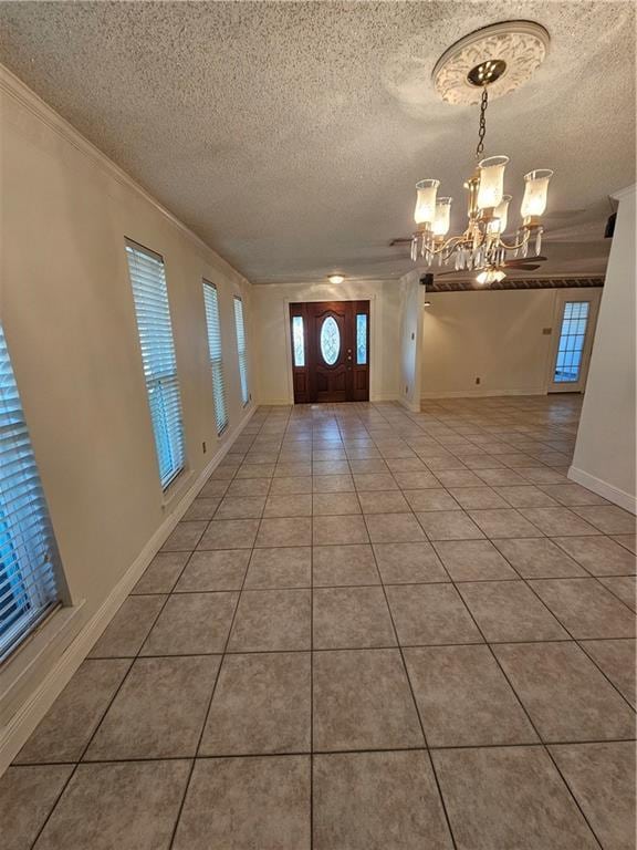 tiled entrance foyer with a textured ceiling, an inviting chandelier, and crown molding