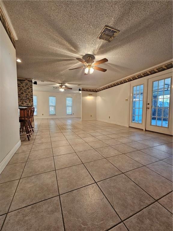 empty room with ceiling fan, light tile patterned floors, and a textured ceiling