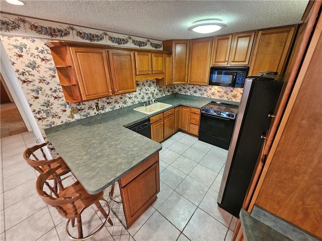 kitchen featuring sink, a kitchen breakfast bar, kitchen peninsula, a textured ceiling, and black appliances