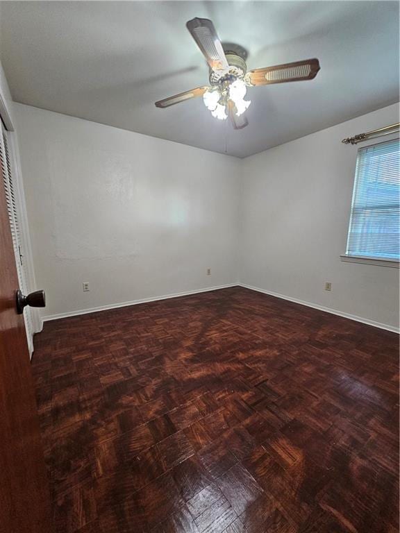 empty room featuring dark parquet floors and ceiling fan