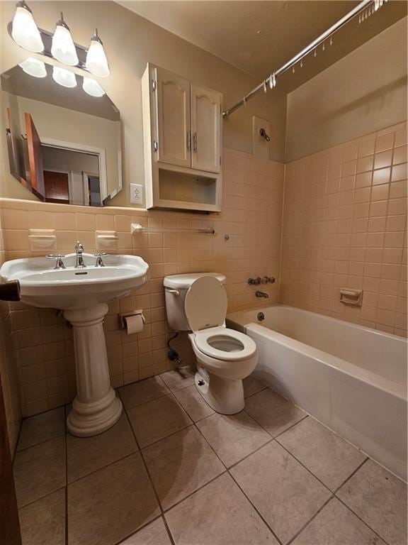 bathroom with tile patterned flooring, toilet, tile walls, and tiled shower / bath