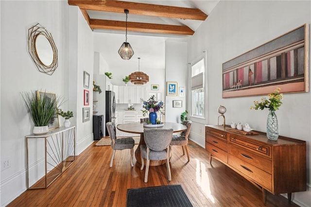 dining space with beam ceiling, light wood-type flooring, and high vaulted ceiling