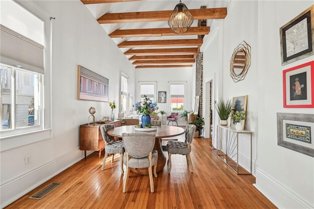 dining area featuring a chandelier, beam ceiling, and light wood-type flooring