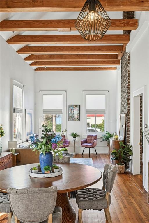 dining area featuring beam ceiling, plenty of natural light, and hardwood / wood-style flooring