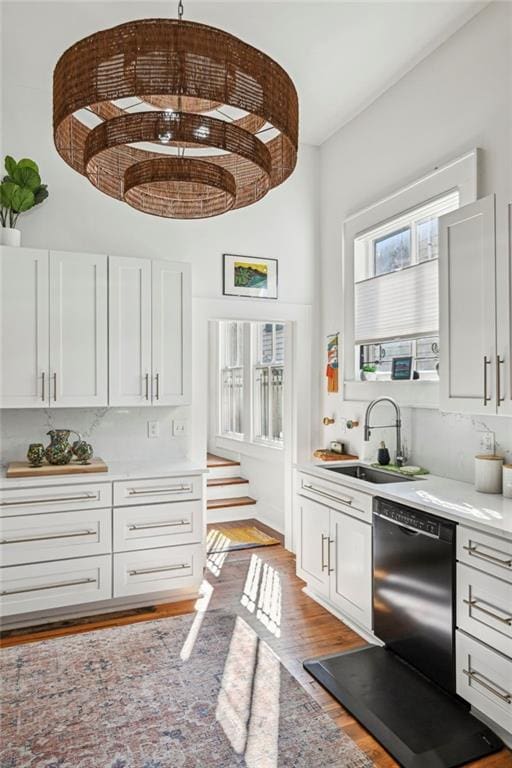 interior space with sink, light wood-type flooring, black dishwasher, white cabinetry, and brick ceiling