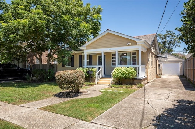 bungalow-style home featuring a porch, a garage, an outbuilding, and a front yard