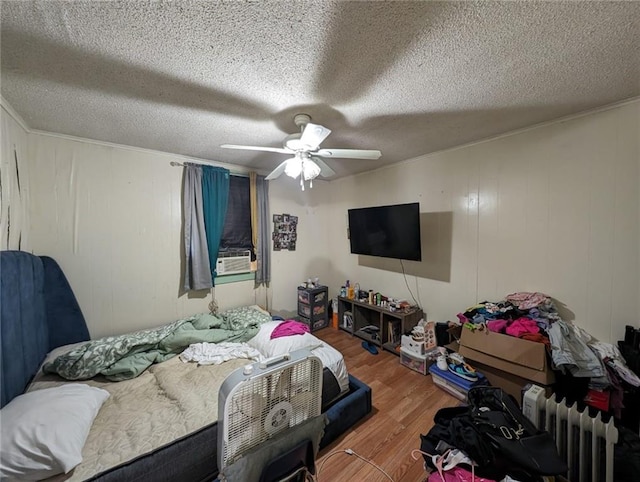 bedroom with ceiling fan, radiator heating unit, a textured ceiling, and hardwood / wood-style floors