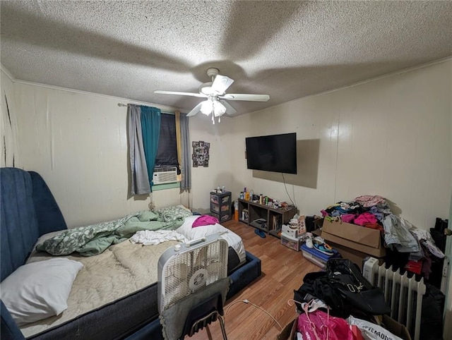 bedroom featuring ceiling fan, radiator, wood-type flooring, and a textured ceiling