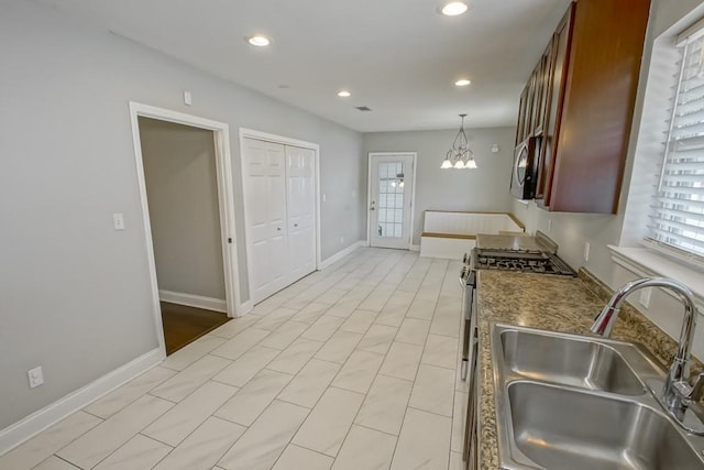 kitchen with hanging light fixtures, stainless steel range with gas cooktop, sink, and a notable chandelier