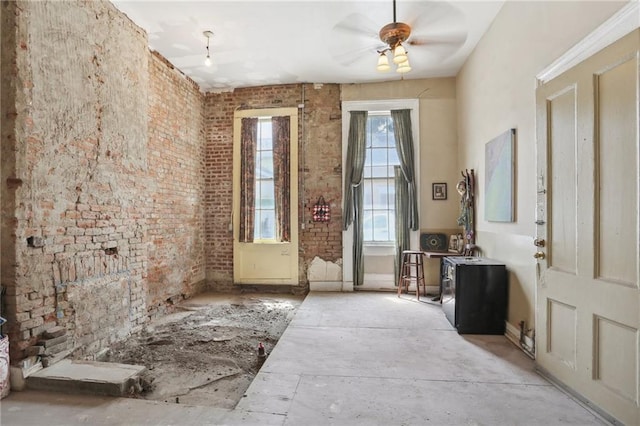 entrance foyer featuring ceiling fan and brick wall